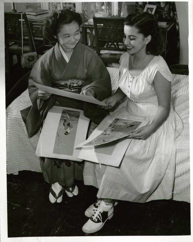 Japanese student, Cecilia Ezoe, showing classmate Raquel Rivera some art work